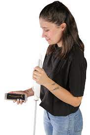 Image of young lady holding a WeWALK cane in one hand, and smartphone her other hand