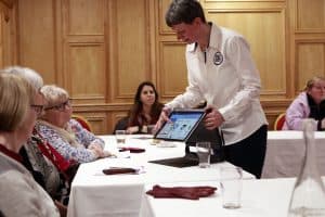 Photo of a member of Sight and Sound Technology staff demonstrating a Microsoft surface to a group of older women. 