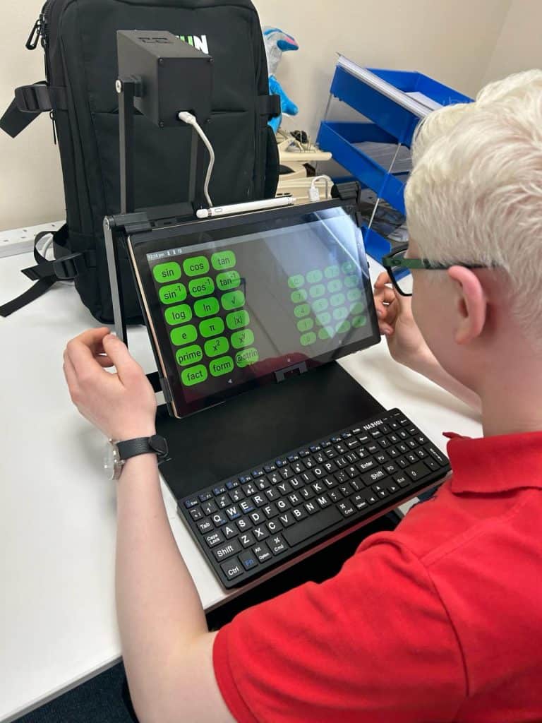 Nathan sits on front of his device, which is a 14 inch tablet and a large print keyboard.