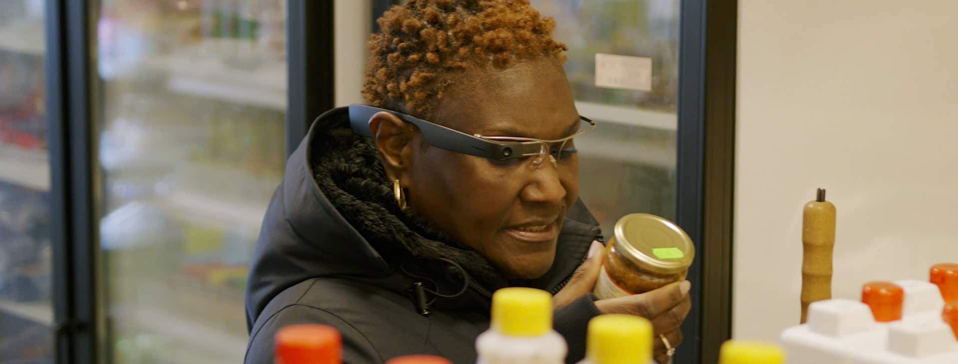 A woman uses Envision smart glasses while in the supermarket.